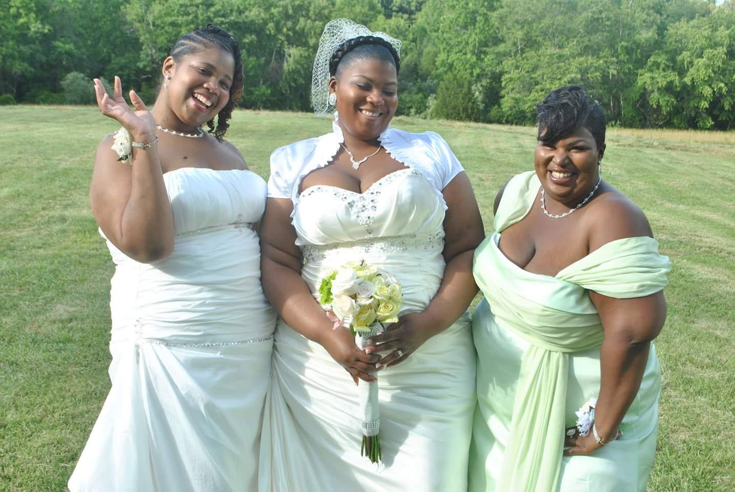 A bride smiling outdoors with members of her wedding party